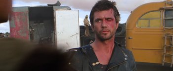 Movie still from “The Road Warrior” (1981), directed by George Miller – A person wearing a leather jacket; Close Up shot, Over the shoulder angle