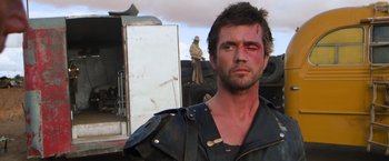 Movie still from “The Road Warrior” (1981), directed by George Miller – A person wearing a leather jacket; Close Up shot, Over the shoulder angle