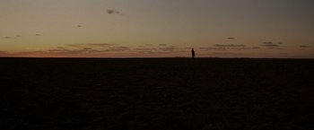 Movie still from “Mad Max Beyond Thunderdome” (1985), directed by George Miller – A person standing in a field at sunset; Extreme Wide shot, Low angle