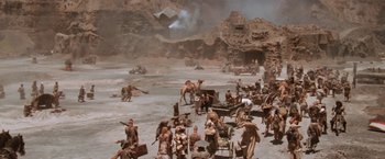 Movie still from “Mad Max Beyond Thunderdome” (1985), directed by George Miller – A group of people sitting on top of a dirt field; Extreme Wide shot, High angle