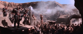 Movie still from “Mad Max Beyond Thunderdome” (1985), directed by George Miller – A crowd of people standing around a building; Wide shot, Low angle