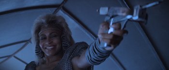 Movie still from “Mad Max Beyond Thunderdome” (1985), directed by George Miller – A woman holding a wii remote in her hand; Close Up shot, Low angle