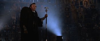 Movie still from “Mad Max Beyond Thunderdome” (1985), directed by George Miller – A man in a black robe holding up a staff; Medium shot, Low angle