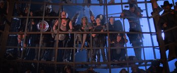 Movie still from “Mad Max Beyond Thunderdome” (1985), directed by George Miller – A group of people standing next to each other in a cage; Wide shot, Low angle