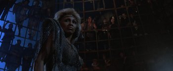 Movie still from “Mad Max Beyond Thunderdome” (1985), directed by George Miller – A woman in a silver dress standing in front of a mirror; Medium shot, Low angle