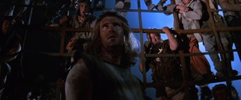 Movie still from “Mad Max Beyond Thunderdome” (1985), directed by George Miller – A group of men standing next to each other in a room; Medium shot, Low angle
