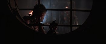 Movie still from “Mad Max Beyond Thunderdome” (1985), directed by George Miller – A man looking at his cell phone in a dark room; Close Up shot, Over the shoulder angle