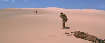 Movie still from “Mad Max Beyond Thunderdome” (1985), directed by George Miller – A man standing on top of a sand dune; Extreme Wide shot, High angle