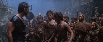 Movie still from “Mad Max Beyond Thunderdome” (1985), directed by George Miller – A group of people standing around each other in a room; Wide shot, High angle