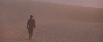 Movie still from “Mad Max Beyond Thunderdome” (1985), directed by George Miller – A person walking in the sand on a beach; Wide shot, Low angle