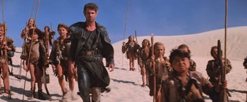 Movie still from “Mad Max Beyond Thunderdome” (1985), directed by George Miller – A group of people walking up a dirt hill; Wide shot, Low angle