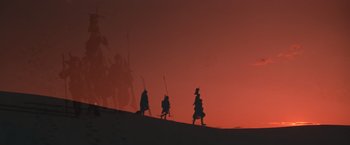 Movie still from “Mad Max Beyond Thunderdome” (1985), directed by George Miller – A group of people walking up a hill at sunset; Extreme Wide shot, Low angle