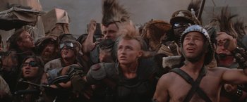 Movie still from “Mad Max Beyond Thunderdome” (1985), directed by George Miller – A group of people in a field with a sky in the background; Close Up shot, Low angle