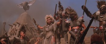Movie still from “Mad Max Beyond Thunderdome” (1985), directed by George Miller – A group of people dressed in costumes and holding guns; Medium shot, Low angle