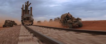 Movie still from “Mad Max Beyond Thunderdome” (1985), directed by George Miller – A train traveling down train tracks next to a dirt field; Extreme Wide shot, Low angle