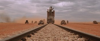Movie still from “Mad Max Beyond Thunderdome” (1985), directed by George Miller – A train is traveling down the tracks in the middle of the desert; Extreme Wide shot, Low angle