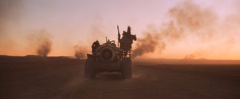 Movie still from “Mad Max Beyond Thunderdome” (1985), directed by George Miller – A man driving a four wheeled vehicle in the middle of the desert; Extreme Wide shot, Low angle