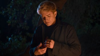 Movie still from “Mae Martin: SAP” (2023), directed by Abbi Jacobson – A young man looking at his cell phone in the dark; Medium shot, Over the shoulder angle