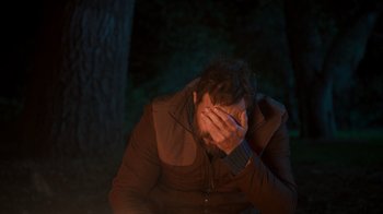 Movie still from “Mae Martin: SAP” (2023), directed by Abbi Jacobson – A man sitting in the dark holding his head in his hands; Close Up shot, Over the shoulder angle