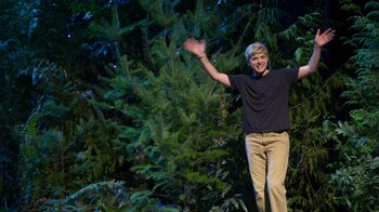 Movie still from “Mae Martin: SAP” (2023), directed by Abbi Jacobson – A young man standing in front of a tree waving; Wide shot, Low angle
