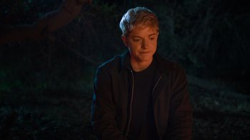 Movie still from “Mae Martin: SAP” (2023), directed by Abbi Jacobson – A man with blonde hair sitting in the dark; Close Up shot, Over the shoulder angle