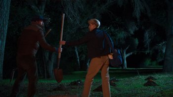 Movie still from “Mae Martin: SAP” (2023), directed by Abbi Jacobson – A man holding a shovel in a park at night; Wide shot, Over the shoulder angle