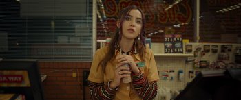 Movie still from “Maggie Moore(s)” (2023), directed by John Slattery – A woman holding a cup of coffee in a store; Medium shot, Over the shoulder angle