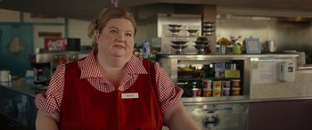 Movie still from “Maggie Moore(s)” (2023), directed by John Slattery – A woman standing in front of an oven in a kitchen; Medium shot, Low angle