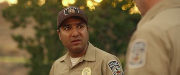 Movie still from “Maggie Moore(s)” (2023), directed by John Slattery – A police officer wearing a brown hat and a brown uniform; Close Up shot, Over the shoulder angle