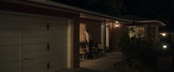 Movie still from “Maggie Moore(s)” (2023), directed by John Slattery – An older man standing in front of a house at night; Wide shot, Low angle