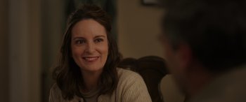 Movie still from “Maggie Moore(s)” (2023), directed by John Slattery – A woman smiling for the camera while sitting in a chair; Close Up shot, Over the shoulder angle
