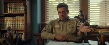 Movie still from “Maggie Moore(s)” (2023), directed by John Slattery – A police officer sitting at a table in front of a window; Close Up shot, Over the shoulder angle