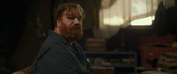 Movie still from “Maggie Moore(s)” (2023), directed by John Slattery – A man with a beard is sitting in a room; Close Up shot, Over the shoulder angle