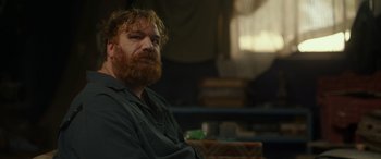 Movie still from “Maggie Moore(s)” (2023), directed by John Slattery – A man with a beard sitting in front of a window; Close Up shot, Over the shoulder angle