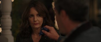 Movie still from “Maggie Moore(s)” (2023), directed by John Slattery – A woman is looking in the mirror while a man holds a blue object; Close Up shot, Over the shoulder angle
