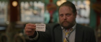 Movie still from “Maggie Moore(s)” (2023), directed by John Slattery – A man holding a business card in front of him; Extreme Close Up shot, Over the shoulder angle