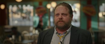 Movie still from “Maggie Moore(s)” (2023), directed by John Slattery – A person wearing a suit and a tie; Close Up shot, Over the shoulder angle