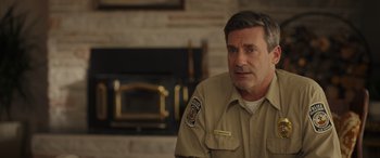 Movie still from “Maggie Moore(s)” (2023), directed by John Slattery – A person wearing a uniform near a fire place; Close Up shot, Over the shoulder angle