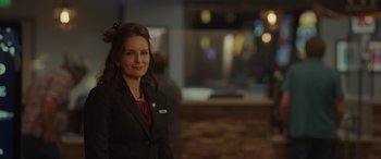 Movie still from “Maggie Moore(s)” (2023), directed by John Slattery – A woman standing in a room wearing a suit and tie; Close Up shot, Over the shoulder angle