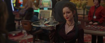 Movie still from “Maggie Moore(s)” (2023), directed by John Slattery – A woman holding a tray of drinks at a party; Medium shot, Over the shoulder angle