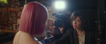 Movie still from “Maggie Moore(s)” (2023), directed by John Slattery – A woman is being interviewed by a camera man; Close Up shot, Over the shoulder angle