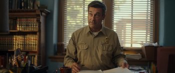 Movie still from “Maggie Moore(s)” (2023), directed by John Slattery – A man in a uniform writing on a piece of paper; Close Up shot, Over the shoulder angle