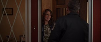 Movie still from “Maggie Moore(s)” (2023), directed by John Slattery – A woman standing in front of a door smiling at a man; Medium shot, Over the shoulder angle