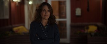 Movie still from “Maggie Moore(s)” (2023), directed by John Slattery – A woman standing with her arms crossed in front of a window; Close Up shot, Over the shoulder angle