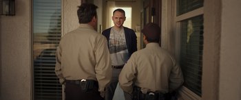 Movie still from “Maggie Moore(s)” (2023), directed by John Slattery – A group of men standing in a hallway talking to each other; Medium shot, Over the shoulder angle