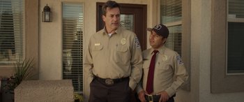 Movie still from “Maggie Moore(s)” (2023), directed by John Slattery – A couple of men standing next to each other on a porch; Medium shot, Over the shoulder angle