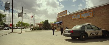 Movie still from “Maggie Moore(s)” (2023), directed by John Slattery – Two men walking down the street in front of a building; Extreme Wide shot, Over the shoulder angle