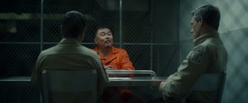 Movie still from “Maggie Moore(s)” (2023), directed by John Slattery – A group of men sitting at a table in a jail cell; Medium shot, Over the shoulder angle