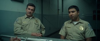 Movie still from “Maggie Moore(s)” (2023), directed by John Slattery – A couple of men sitting next to each other in front of a table; Medium shot, Over the shoulder angle