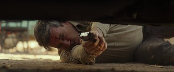 Movie still from “Maggie Moore(s)” (2023), directed by John Slattery – A man laying on the ground with a gun pointed at him; Close Up shot, High angle